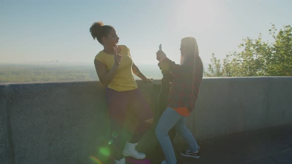 Excited Diverse Women Skateboarders Taking Funny Selfie Shot at Sunrise