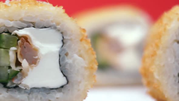 Appetizing baked sushi with shrimps, fish, rice, cucumber rotate on a light surface