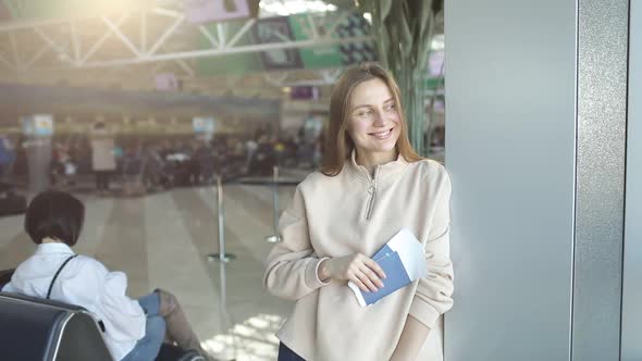 Happy cheerful young woman standing in front of camera, getting visa, holding tickets passport 
