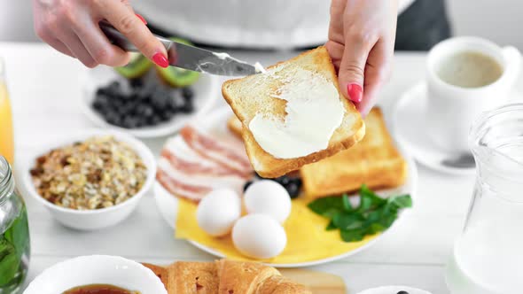 Closeup Female Hand Spreading Butter on Fried Bread Toast Using Knife Enjoying Breakfast Food