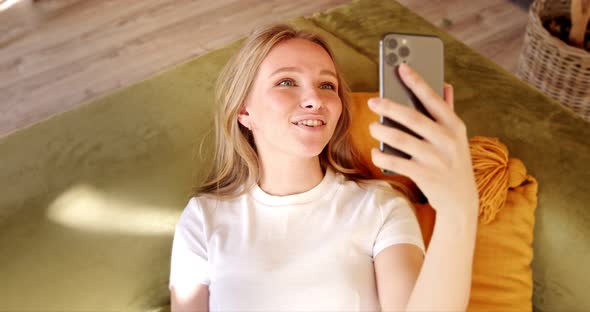 Young woman making video call or chat online on mobile phone at home