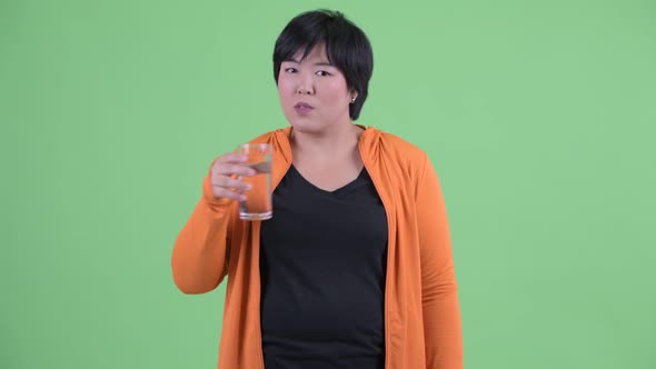 Happy Young Overweight Asian Woman Drinking Water and Giving Thumbs Up Ready for Gym