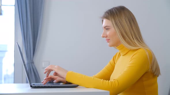 Young blonde woman working on laptop computer at home in 4k stock video clip