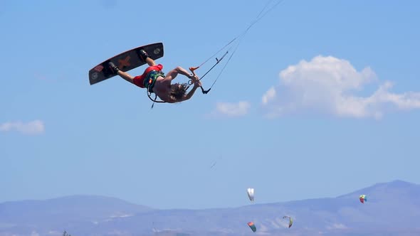 A man kiteboarding and doing a jumping trick on a kite board.