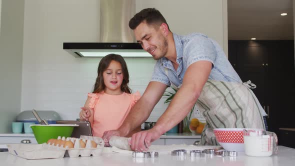 Happy caucasian father and daughter baking together in kitchen