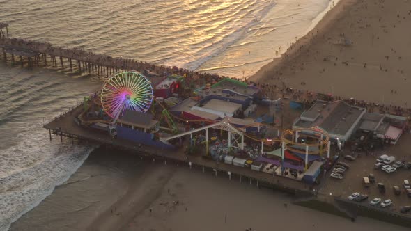 AERIAL: Flying Towards Santa Monica Pier, Los Angeles at Beautiful Sunset with Tourists, Pedestrians