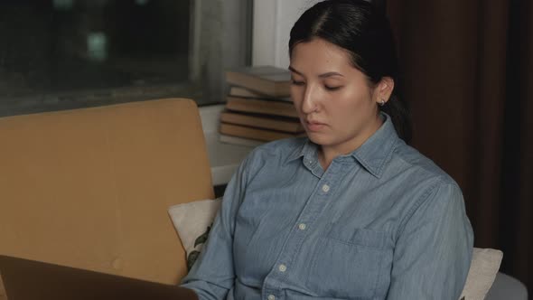 Beautiful woman sitting on Sofa with laptop at home. Typing, browsing Internet.