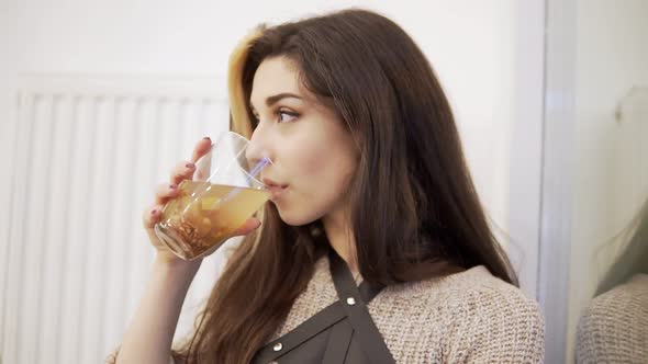 Pretty Young Brunette Woman Drinks From the Glass By the Window