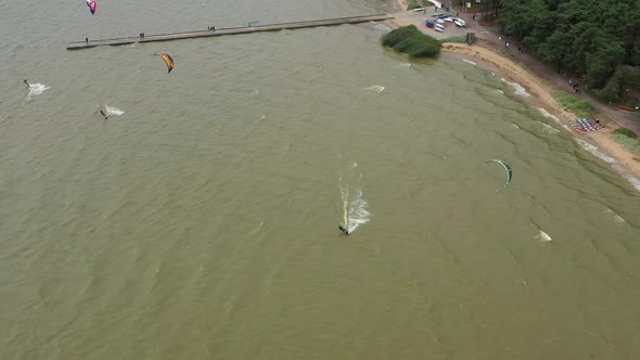 AERIAL: Follow Shot of Isolated Kiteboarder Who Jumps Over Stone Pier on a Cloudy Day