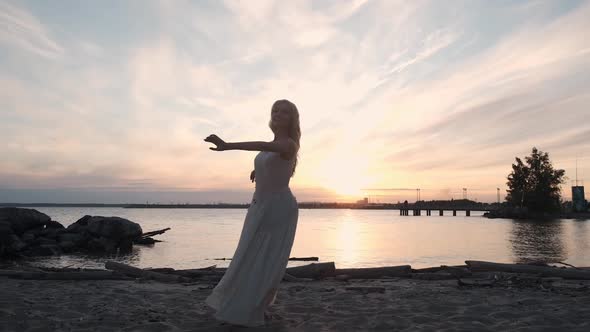 Girl in a Flowing Dress Dancing By the Sea at Sunset