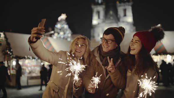 Group of Friends Taking a Selfie with Smartphone on the Christmas Market