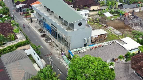 motorbikes driving past a construction building site in Bali Indonesia, aerial