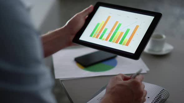 Business Man Researching Charts Graph Using Tablet Computer Pad in Remote Office