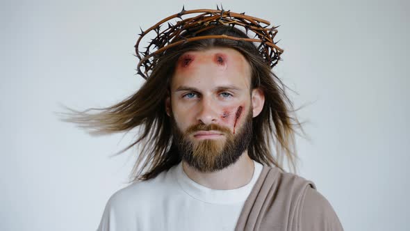 Jesus in a Crown of Thorns with Wounds on His Face Looks Into the Camera