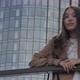 Girl Stands Leaning Against the Railing Against the Backdrop of a Tall Building - VideoHive Item for Sale