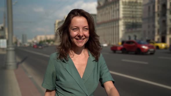 A Smiling Happy Adult Woman Walks and Enjoys the View of the Modern City