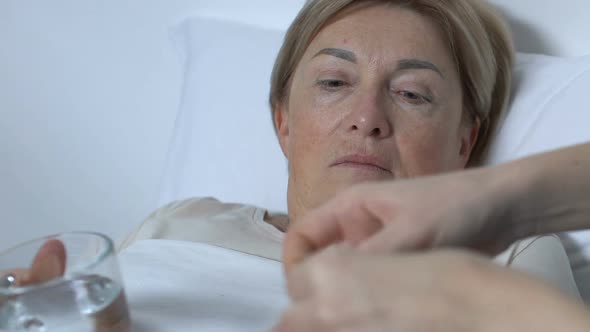 Hospital Volunteer Giving Female Patient Medicine With Glass of Water, Treatment