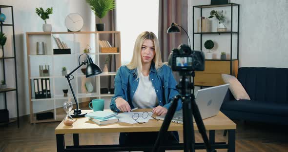 Young Blond Female Blogger Recording Videovlog for Her Internet Followers on Professional Camera