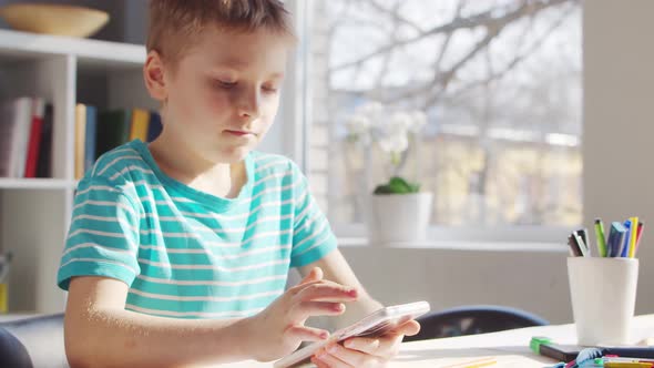 Boy is Doing  Homework at the Table. Cute Child is Learning at Home.