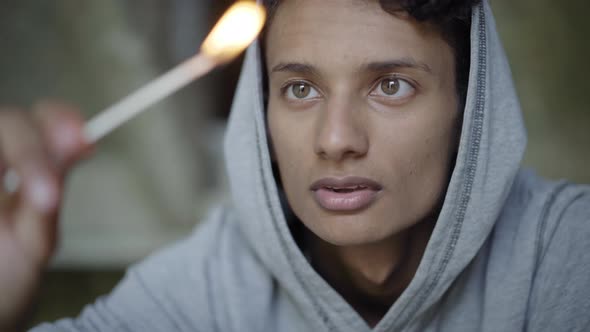 Close-up Face of Mixed-race Boy with Brown Eyes Blowing Out Match and Looking at Camera. Portrait of