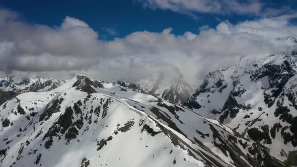 Air flight through mountain clouds over beautiful snow-capped peaks of mountains and glaciers.