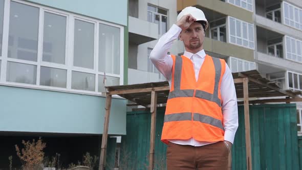 The foreman at the construction site puts on a white helmet.