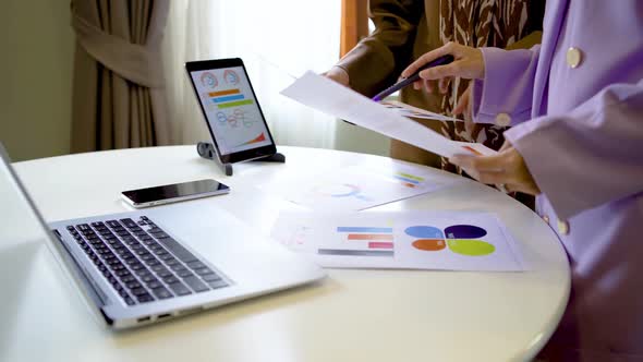 Two muslim business woman accountant pointing paper showing graphic chart on work in the office 