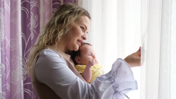 Engaged Young Mother with Curly Hair Holds Little Baby Girl