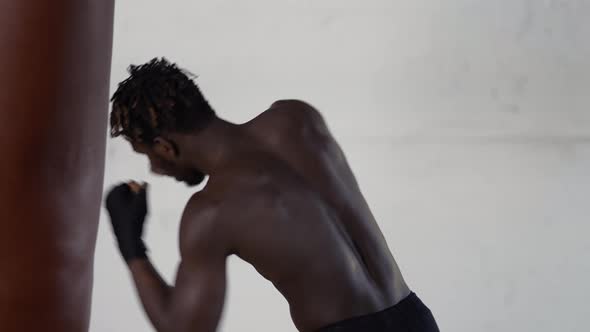 Shirtless African American Male Boxer Enjoying Training at Boxing Studio with Wrapped Hands