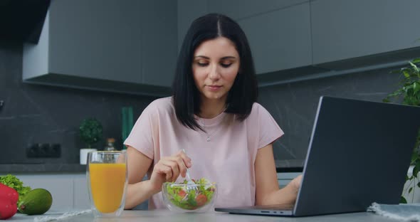 Woman Sitting in front of Computer, Working on it and Eating Vitamin Vegetable salad