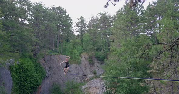 A young woman falls while slacklining on a tightrope.
