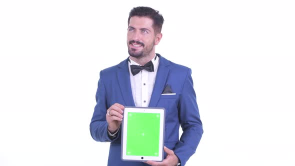 Happy Young Bearded Businessman Thinking While Showing Digital Tablet