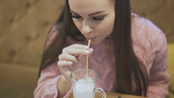 Long Haired Brunette in Pink Pullover Tastes White Coffee