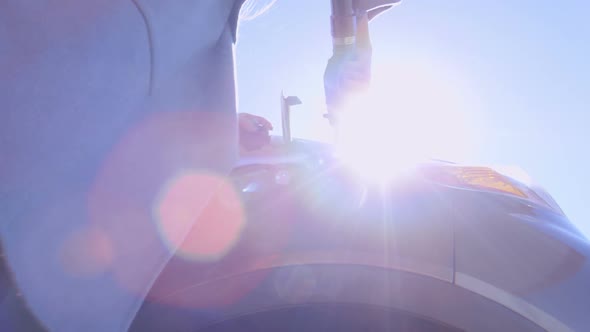 Woman Putting Nozzle into Car Tank