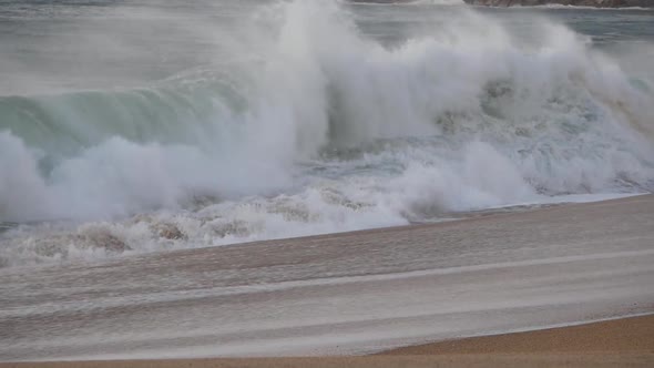 Medium waves crashing by beachfront with beautiful golden sunset light. Water splashes, swashs, move