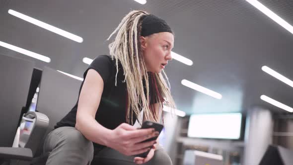 Attractive Young Woman Blogger with Dreadlocks Using Phone at the Airport