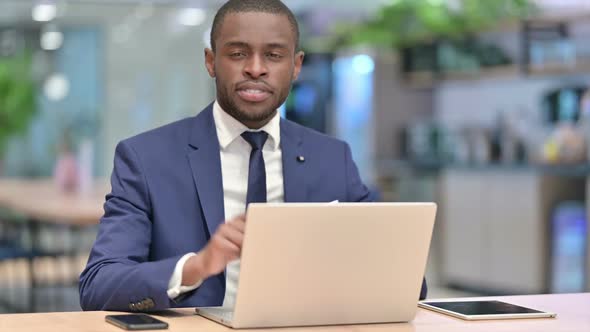 African Businessman with Laptop Pointing at the Camera