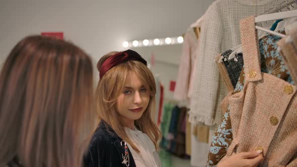 Cheerful Young Ladies Choosing Clothes in Light Modern Showroom