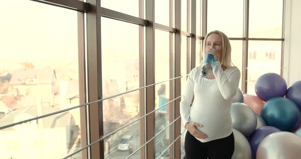 Pregnant Woman Drinking Water in the Gym