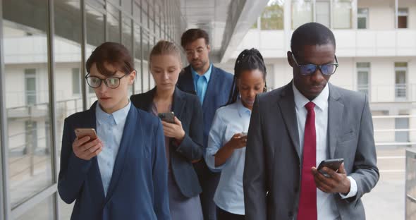 Multiethnic Business Team with Gadgets Going Along Urban Building