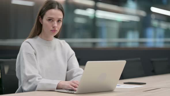 Woman Looking at Camera while working on Laptop