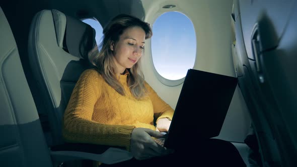 Lovely Woman Is Working on a Laptop on a Plane at Sunrise