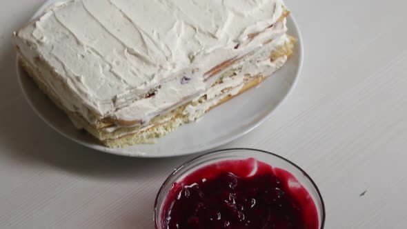 Cake Made From Biscuit Cakes Smeared With Cream. Nearby Is A Container With Cherry Filling For The C