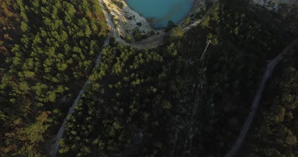 Aerial shot of an abandoned quarry in the middle of a pine forest. Clear blue lake super deep. Shot