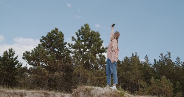 Young Woman Raises Hand with a Phone High Trying To Catch Lost Cellular Signal