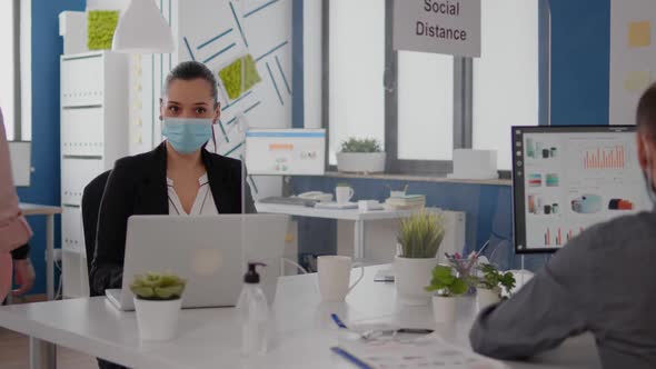 Coworkers with Protection Face Masks Working Together in New Normal Office