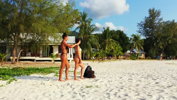 Ladies tan on beautiful resort beach wildlife by aqua blue water and white sand background of Thaila