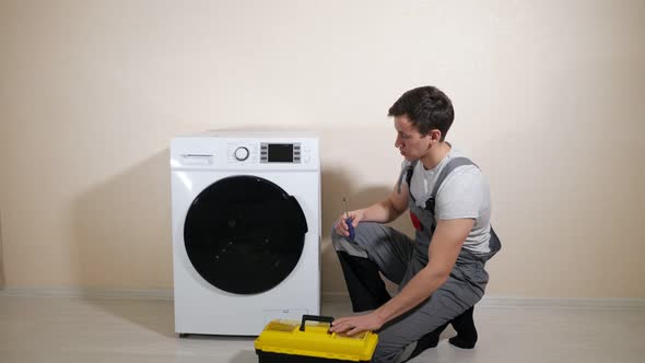 Serviceman with Toolbox Comes to Check Washing Machine