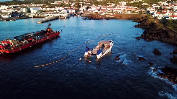 Orbit around a shipwreck at Madalena port in Pico Island. A cargo ship next to it. Azores, Portugal.