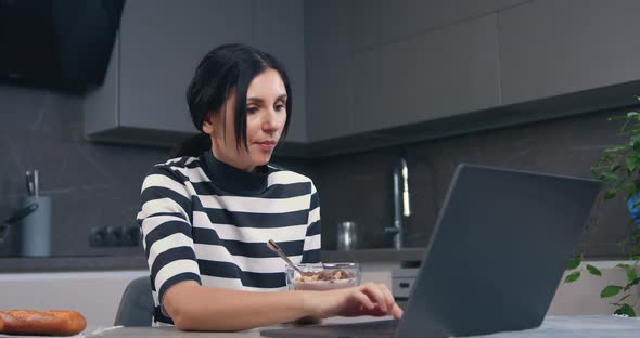 Woman Watching Interesting Program on Laptop and Eating Chocolatey Chip Cookies
